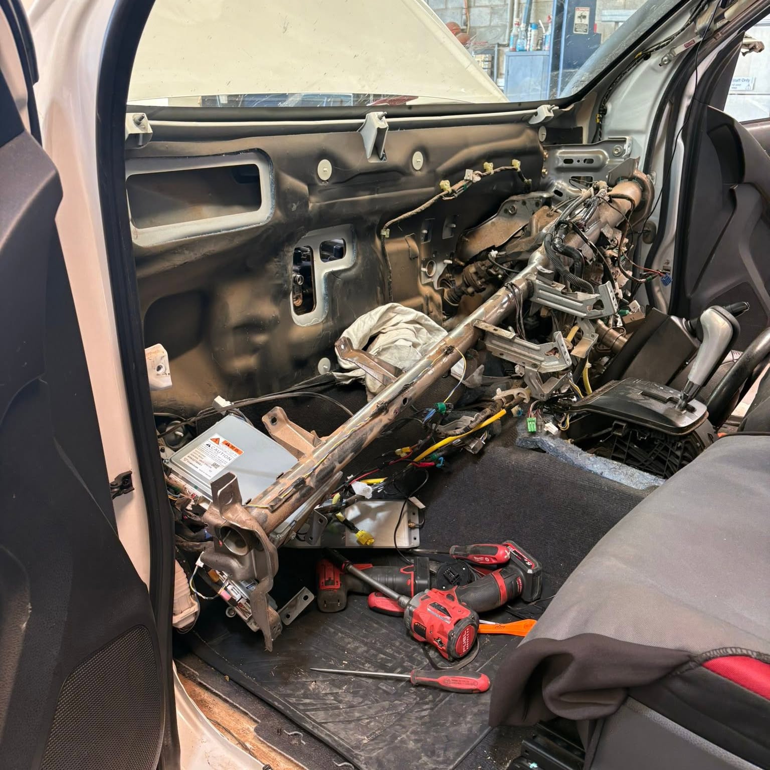 The cross car beam and wiring looms exposed inside the cab, with tools on the floor