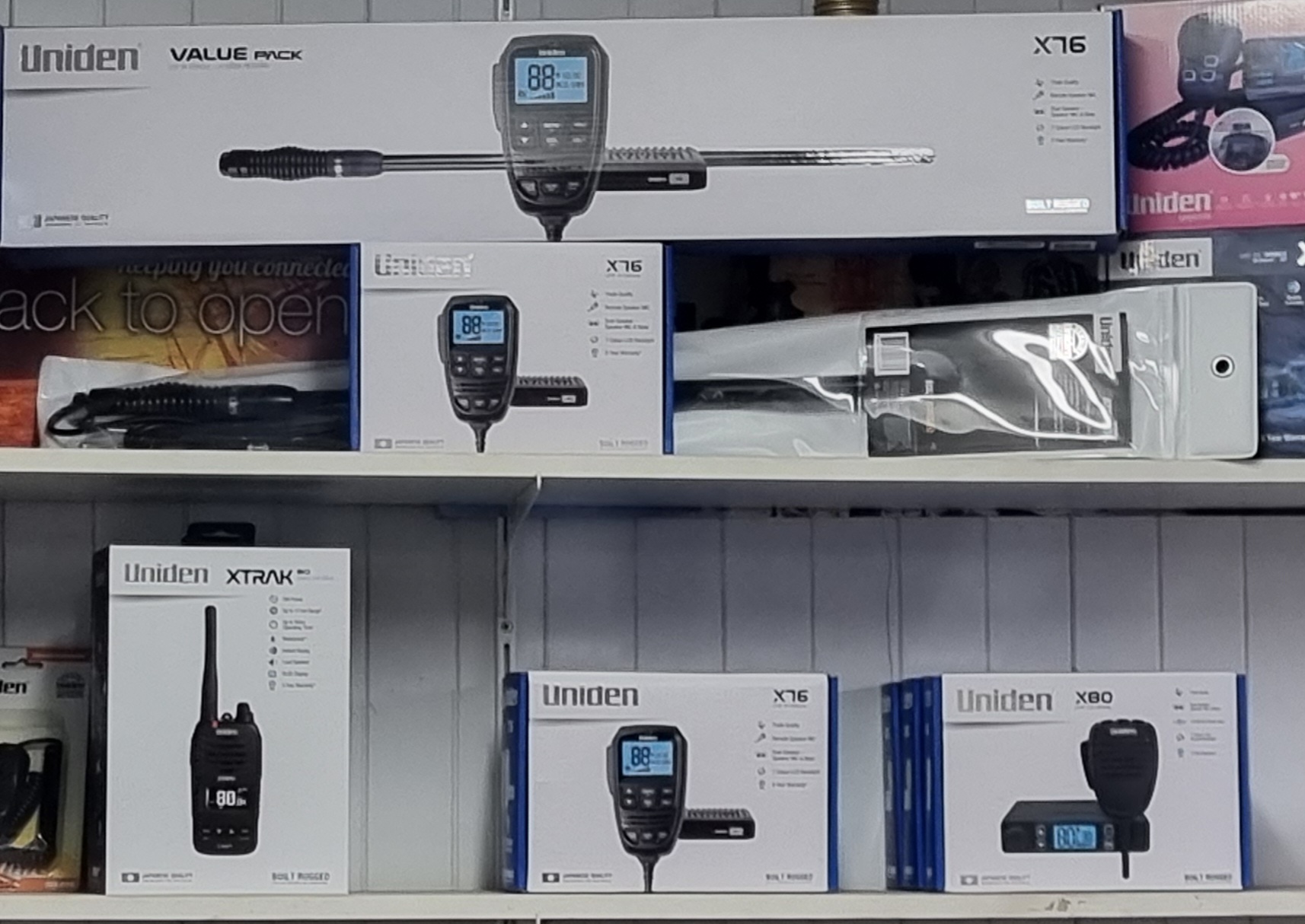 A shelf of Uniden UHF radios including the X76, X80 and XTRAK handheld